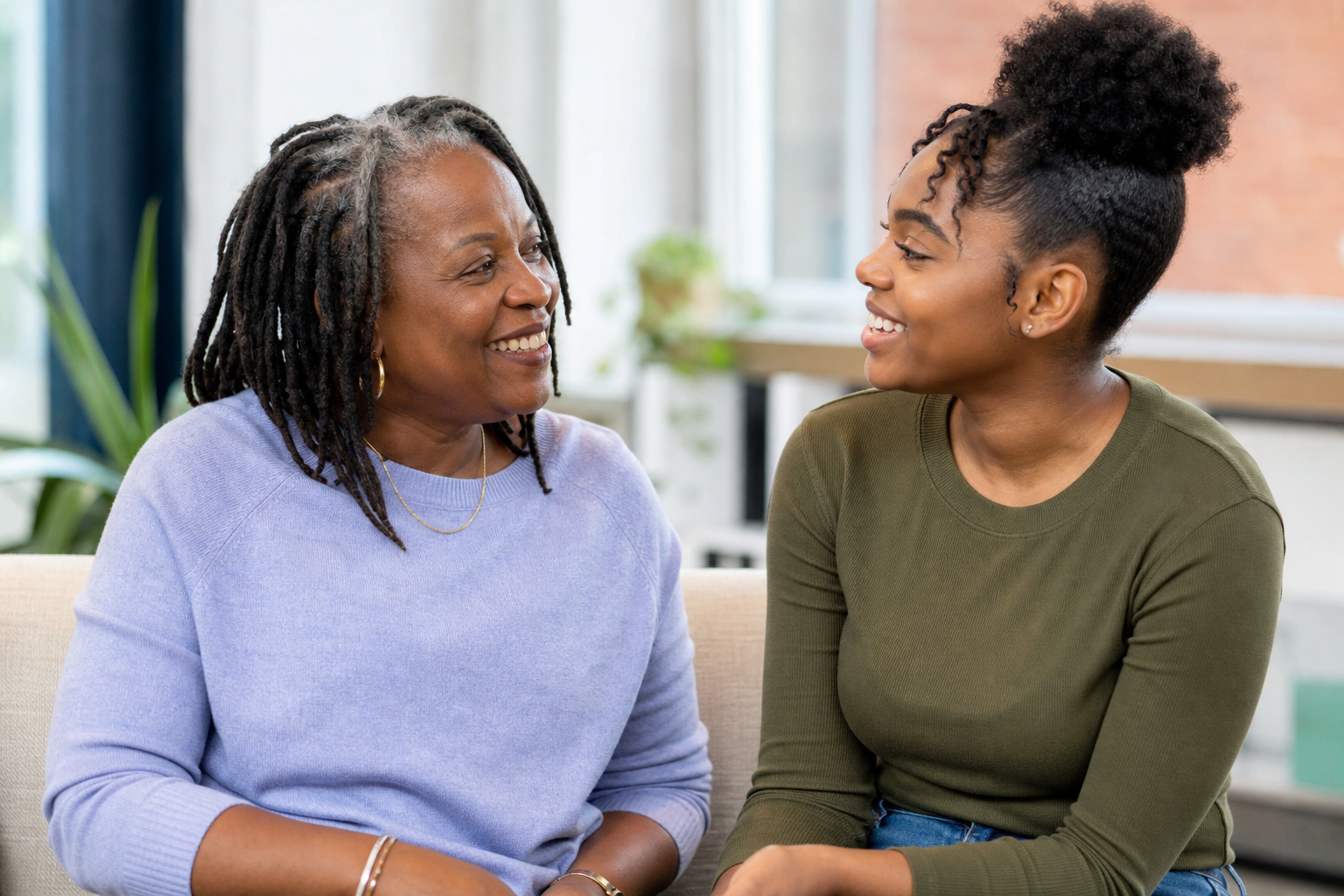 A Black woman talking with a young person, both smiling